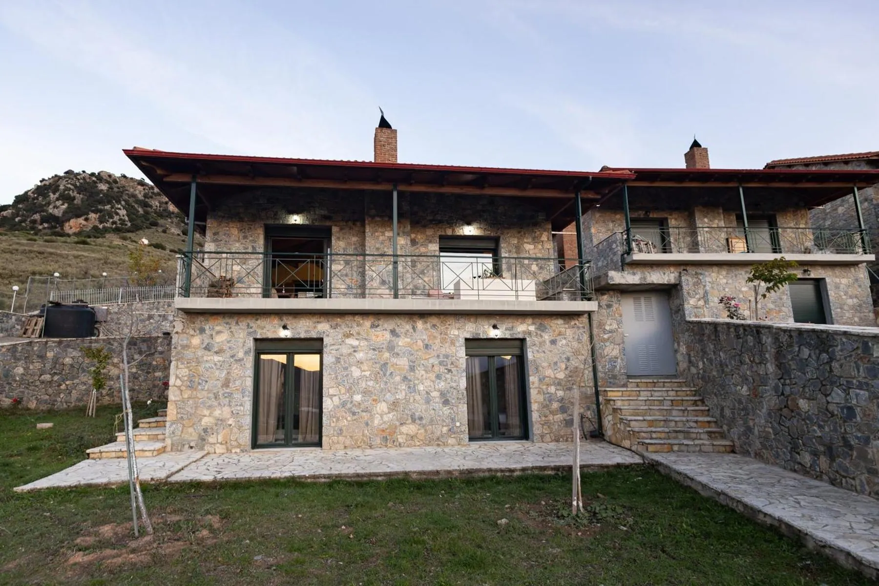 Το διώροφο πέτρινο σαλέ με το ξύλινο μπαλκόνι και τον κήπο με γρασίδι